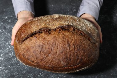 Gri desenli masada bir somun taze ekmekle fırıncı.