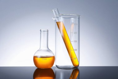 Ayna yüzeyinde gri arka planda turuncu sıvı bulunan farklı camlar.