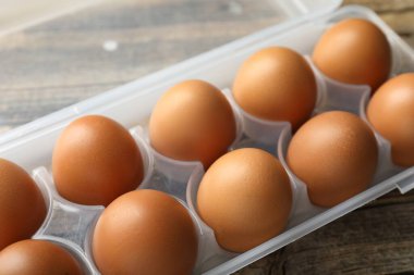 Ahşap masadaki kabın içinde çiğ tavuk yumurtası, yakın plan.