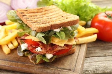 Tahta masada patates kızartmasıyla servis edilen lezzetli sandviç, yakın plan.