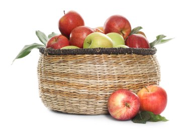 Hasır sepetteki taze elmalar ve beyaz üzerinde yeşil yapraklar.
