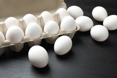 Siyah ahşap masada çiğ tavuk yumurtası, yakın plan.