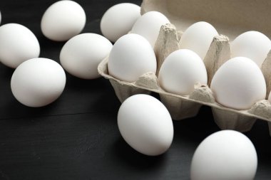 Siyah ahşap masada çiğ tavuk yumurtası, yakın plan.