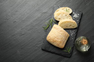 Kesilmiş ciabatta, biberiye, siyah desenli masa üzerinde tuz ve yağ, düz yatak. Metin için boşluk