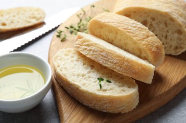 Taze ciabatta, bitkiler ve yağ gri masada, yakın plan.