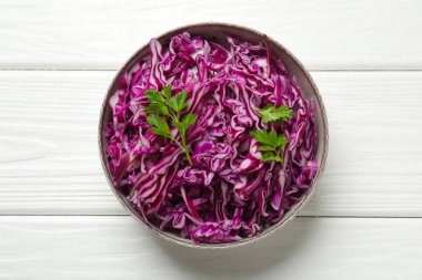 Beyaz ahşap masada maydanozlu, öğütülmüş kırmızı lahana.