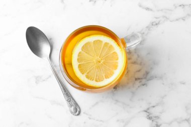 Aromatik çay, fincanda limon ve beyaz mermer masada kaşık, üst manzara.