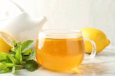 Beyaz mermer masada limonlu, naneli ve çaydanlıklı Aromatik çay, yakın plan.