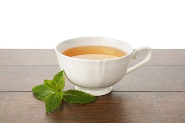 Aromatik çay fincanda ve nane şekeri ahşap masada beyaz arka planda