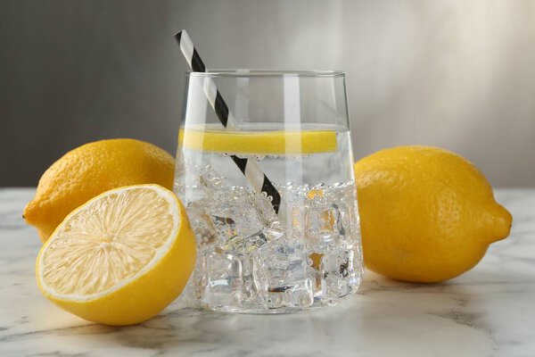 Освежающая вода с лимонами и льдом на белом мраморном столе, крупным планом