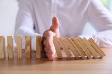 Risk. Tahta masada domino efektini durduran adam, yakın plan.