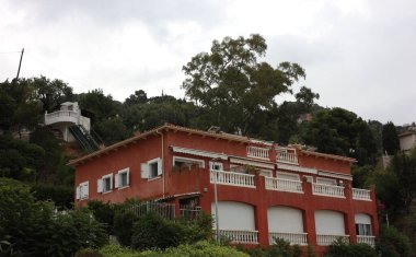 Kırmızı bina ve tepelerdeki birçok farklı bitki.