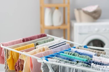 Kurutma askısında bir sürü temiz bebek giysisi var. Kapalı, kapalı.