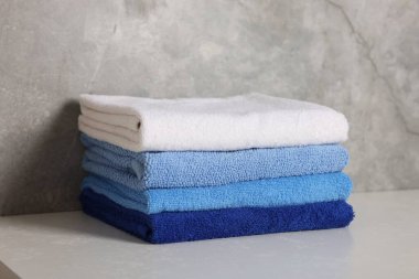 Beyaz masadaki temiz havlular gri arka plana karşı, yakın plan.