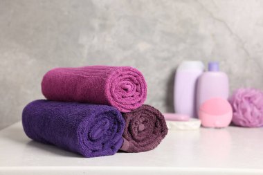 Taze rulo havlular ve kozmetik ürünler beyaz masada, yakın plan.