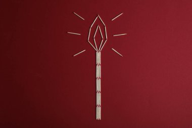 Kırmızı arkaplanda kibritten yapılmış yanan mum, üst görünüm