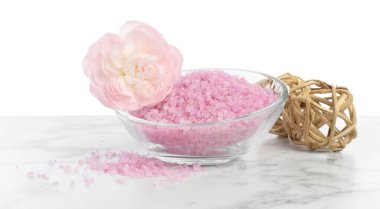 Kasede pembe deniz tuzu ve beyaz arka planda mermer masada güzel bir çiçek.