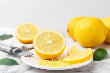 Limon lezzeti, taze meyveler, zester aleti ve yeşil yapraklar açık mermer masada, yakın plan.