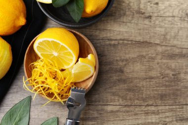 Limon aromalı kase, taze meyve, zester aleti ve ahşap masa üzerinde yeşil yapraklar, düz yatak. Metin için boşluk