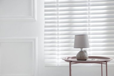 İçerideki pencerenin yanındaki sehpanın üzerinde şık lamba ve yüzükler var. Metin için boşluk