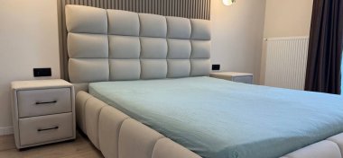 Şık bir yatak odası, içi rahat büyük yatak ve komodinleriyle dolu.