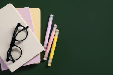 Öğretmenler günün kutlu olsun. Not defteri, kırtasiye malzemesi ve yeşil arka planda gözlük. Metin için boşluk