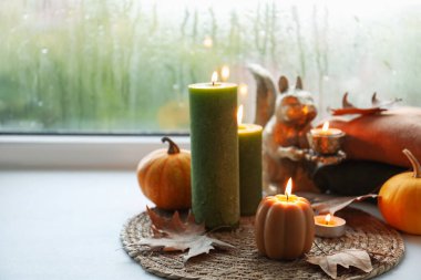Yağmurlu bir günde pencere pervazında mum ve kuru yapraklar yakmak, mesaj atmak için yer açmak. Sonbahar atmosferi