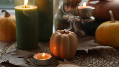 Yağmurlu bir günde pencere pervazında mum ve kuru yapraklar yakmak, yakın çekim. Sonbahar atmosferi