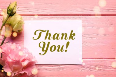 Teşekkür kartı ve çiçekler pembe ahşap arka planda, üst manzara. Bokeh ışıkları