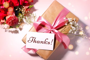 Teşekkürler kart tasarımı, hediye kutusu ve pembe arka planda çiçekler, üst manzara. Bokeh ışıkları