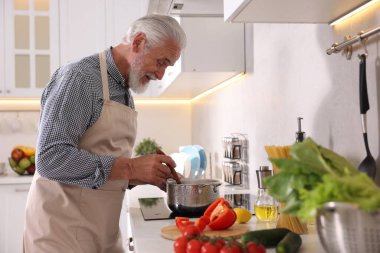 Mutfaktaki mutfağın tepesinde yaşlı bir adam yemek pişiriyor.