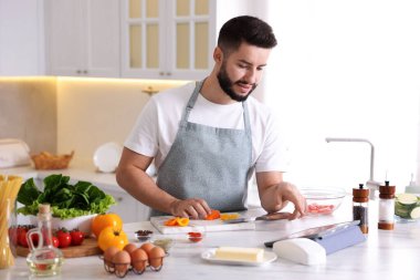 Mutfakta yemek pişirirken tabletten yemek tarifine bakan genç bir adam.