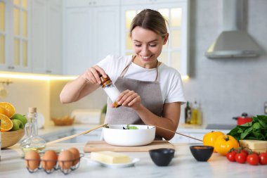 Yemek pişirme süreci. Gülümseyen kadın mutfaktaki masada salata yapıyor.