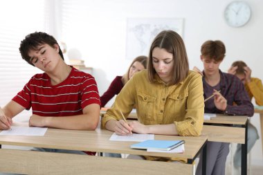 Ahşap masada sınava giren öğrenciler