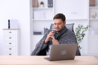 Klima. Ofiste bir bardak sıcak içeceği olan adam soğuk sıcaklıktan muzdarip.