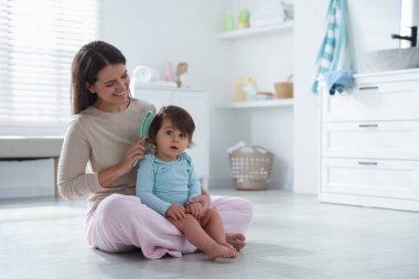 Anne banyoda bebeğinin saçını tarıyor, mesaj atmak için yer açıyor.