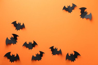 Cadılar Bayramı dekoru. Siyah kağıt yarasalar turuncu arka planda, düz yerde. Metin için boşluk