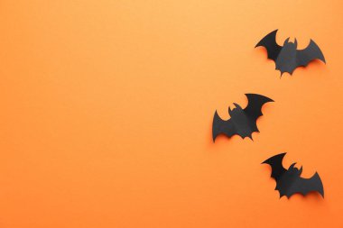 Cadılar Bayramı dekoru. Siyah kağıt yarasalar turuncu arka planda, düz yerde. Metin için boşluk