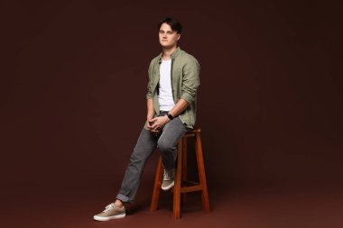 Kahverengi arka planda, kotlu şık bir adam.