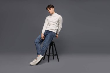 Gri arka planda, kotlu, şık bir adam.