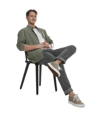 Beyaz arka planda sandalyede şık kotlu bir adam.