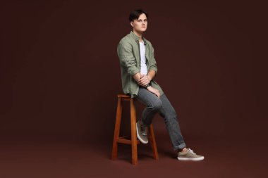 Kahverengi arka planda, kotlu şık bir adam.