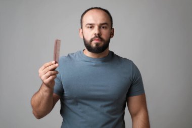 Kellik sorunu. Tarağı gri arkaplanda olan adam