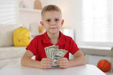 Beyaz masada cep harçlığı tutan küçük çocuk.
