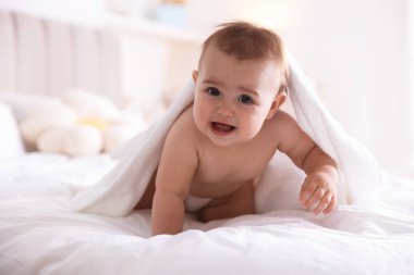 Evde banyo yaptıktan sonra beyaz havluyla sarılmış şirin bir bebek.