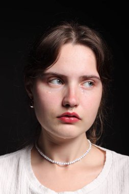 Üzgün genç bir kadın siyah arka planda ağlıyor.