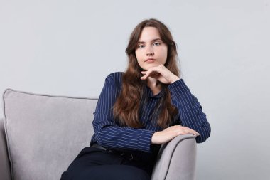 Açık gri arka planda koltukta profesyonel psikoterapist