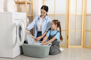 Küçük yardımcı. Anne ve kızı evde çamaşır yıkıyorlar.