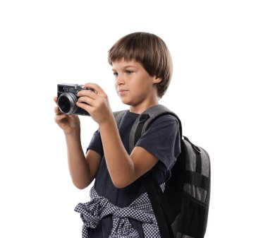Meslek seçimi. Kameralı ve sırt çantalı küçük çocuk beyaz arka planda fotoğrafçı gibi davranıyor.