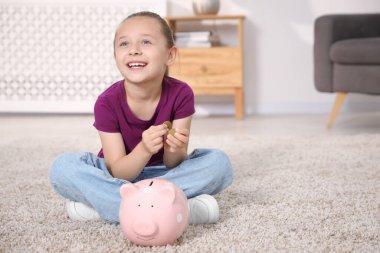 Cep harçlığı ve domuz kumbarası olan küçük kız evde yerde, mesaj atmak için yer var.